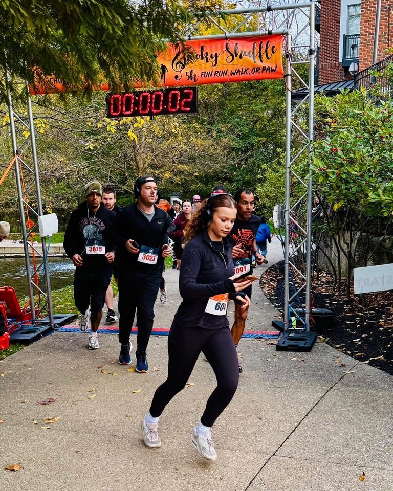 runners in race bibs setting off under the spooky shuffle 5k start arch at creekside
